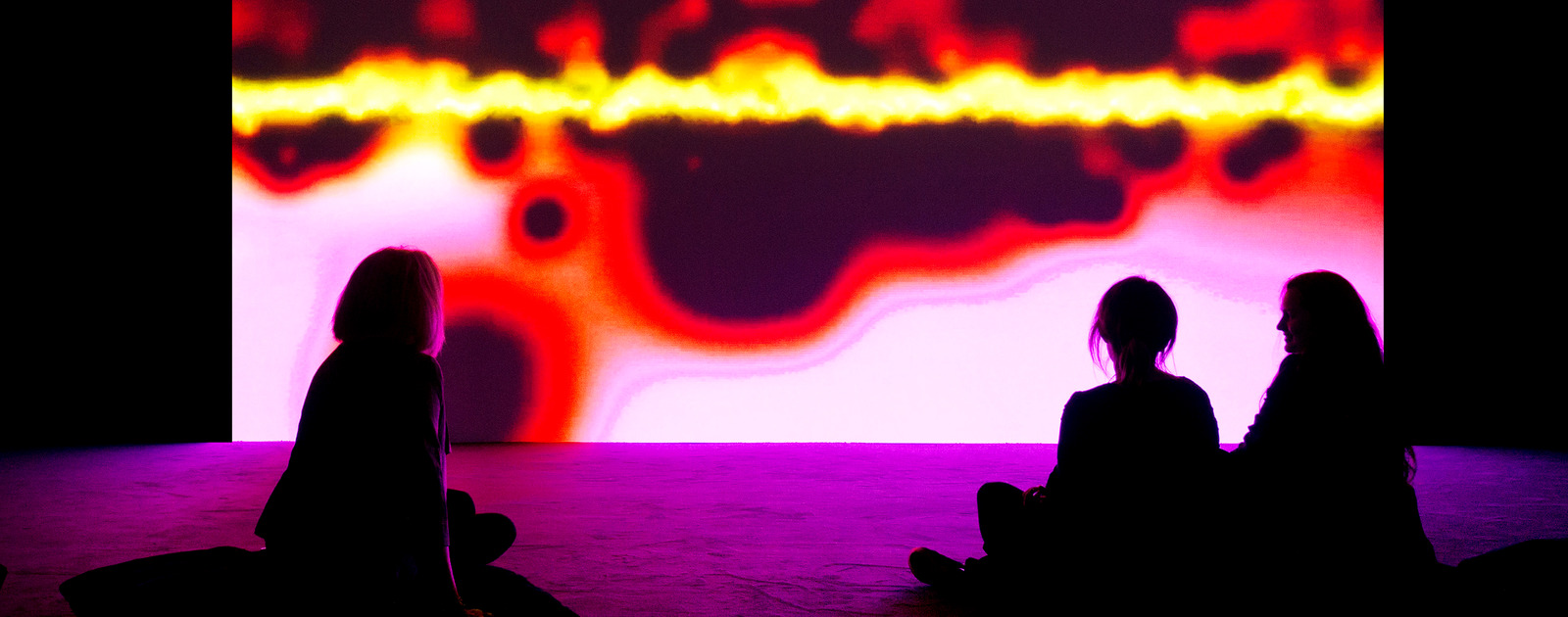 Resounding (Infrared) by Susan Hiller at MIRRORCITY at Hayward Gallery 2014. Visitors watching Colourful Projection by artist, Susan Hiller at Hayward Gallery